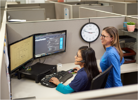 Two women looking at a computer in a cubicle