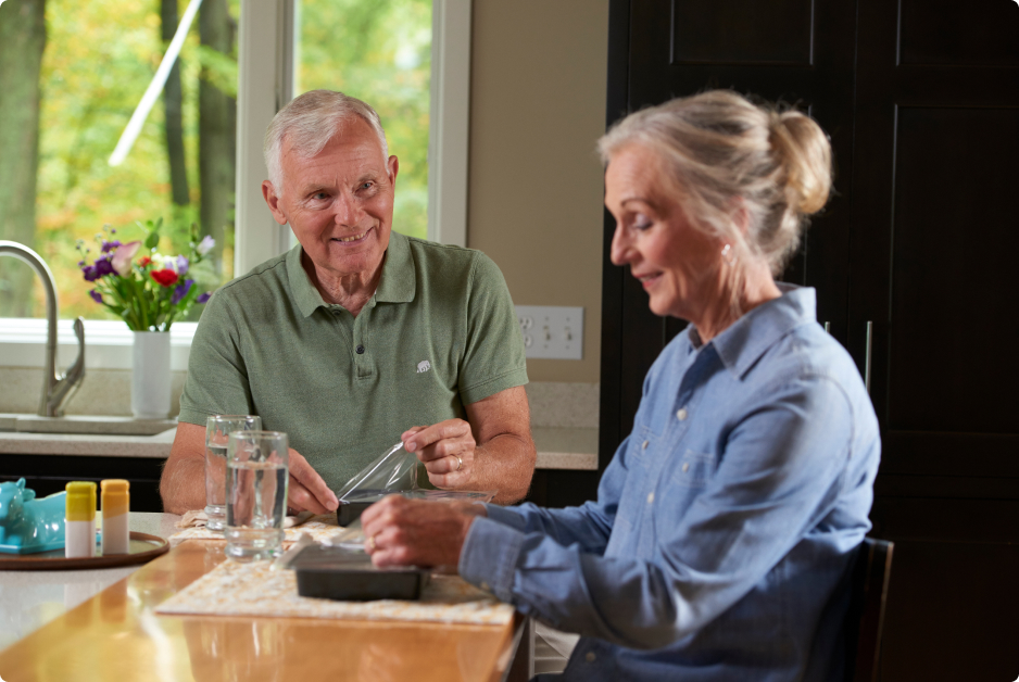 Seniors opening fresh food trays at mealtime.